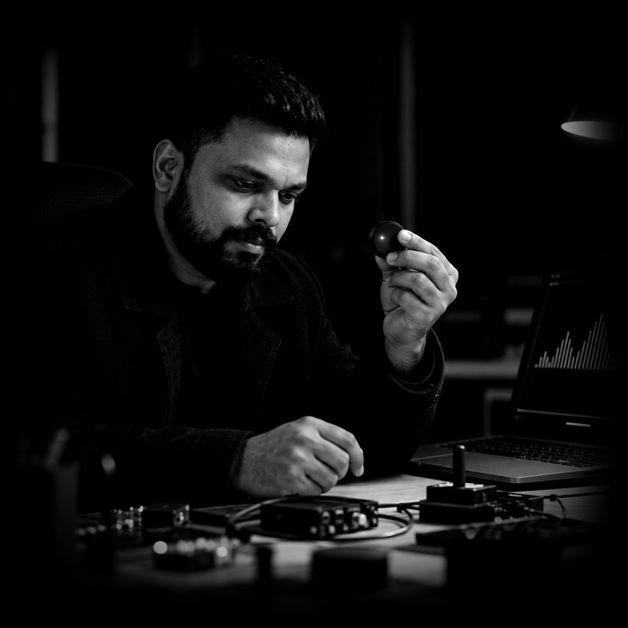 Adharna examining a small wireless sensor beside a laptop